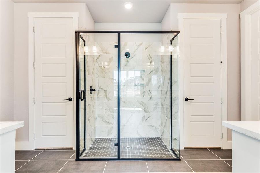 Bathroom featuring a shower with shower door, vanity, and tile patterned flooring