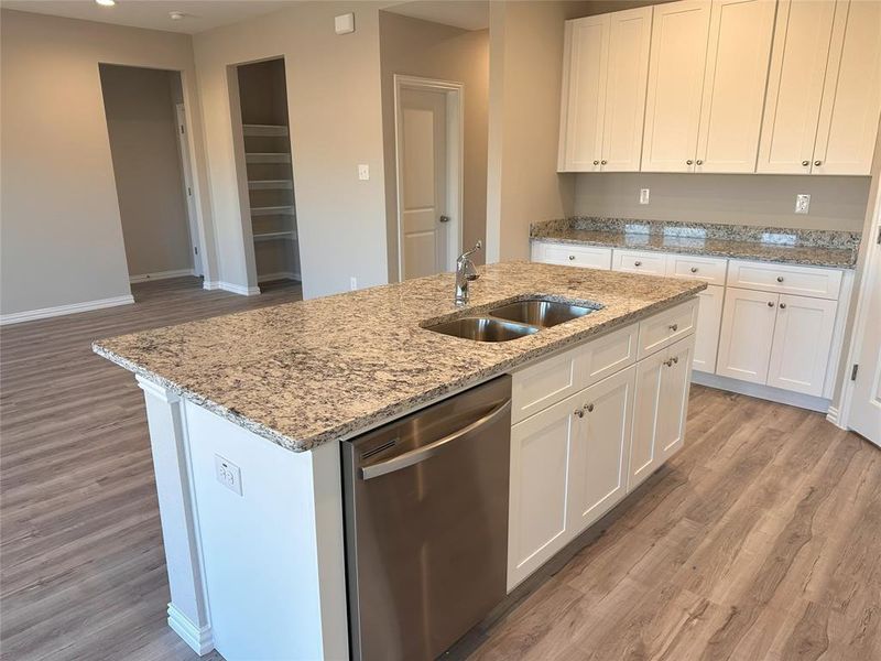 Kitchen with dishwasher, sink, a center island with sink, and white cabinets