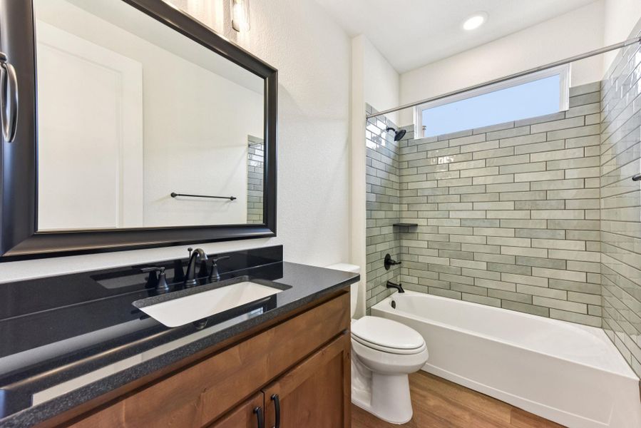 Full bath featuring bathing tub / shower combination, vanity, and light wood-style floors