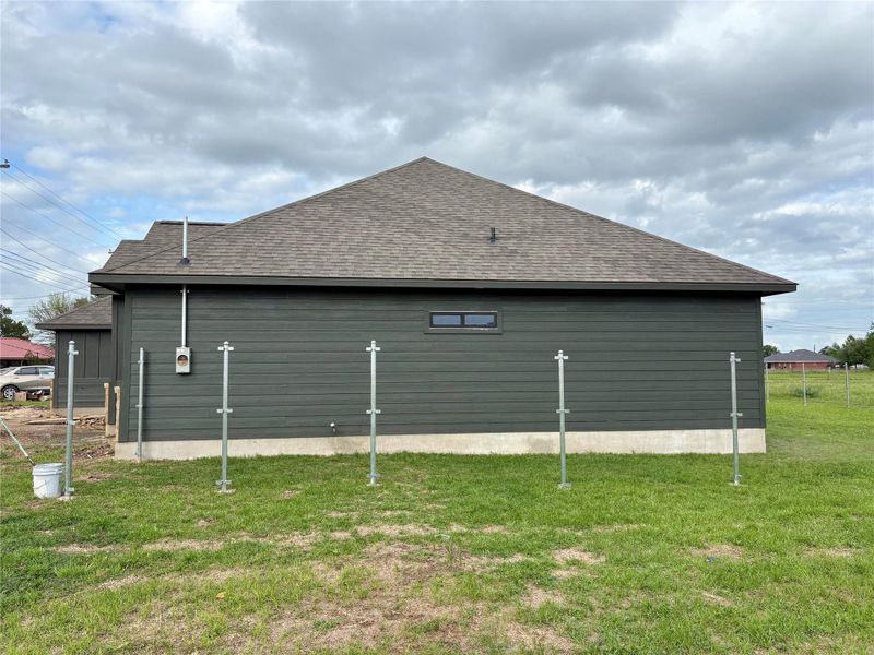 Newly constructed residence featuring dark horizontal siding, shingle roof, and a visible electrical meter box