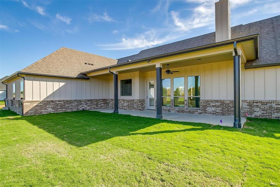 Rear view of house with a patio and a lawn