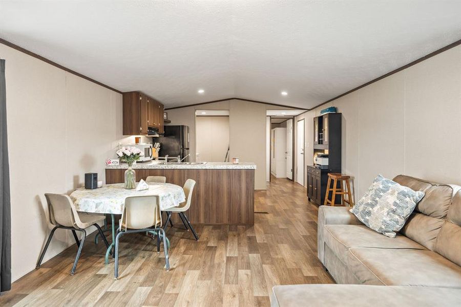 Open-concept living area featuring wood-finish flooring, recessed lighting, and a kitchen island with a stone-look countertop Open-concept living area featuring wood-finish flooring, recessed lighting, and a kitchen island with a stone-look countertop