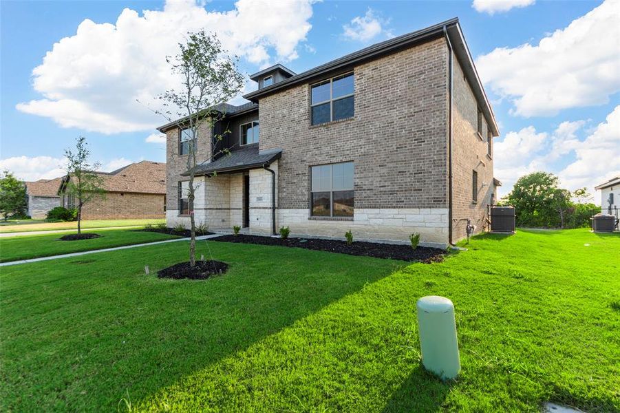 Back of property featuring a lawn, brick siding, and stone siding Back of property featuring a lawn, brick siding, and stone siding