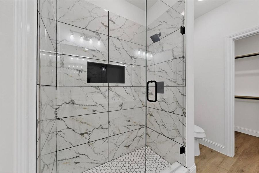 Full bathroom with a marble finish shower, a spacious closet, and wood finished floors