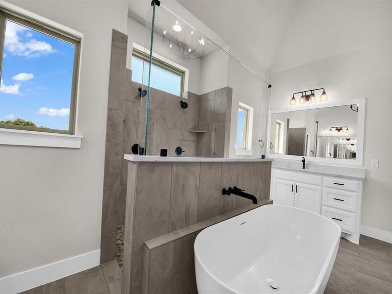 Full bathroom with a freestanding bath, vanity, walk in shower, and light wood-style flooring