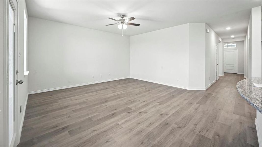 Spacious open-concept room featuring light wood-finish flooring and crisp white walls