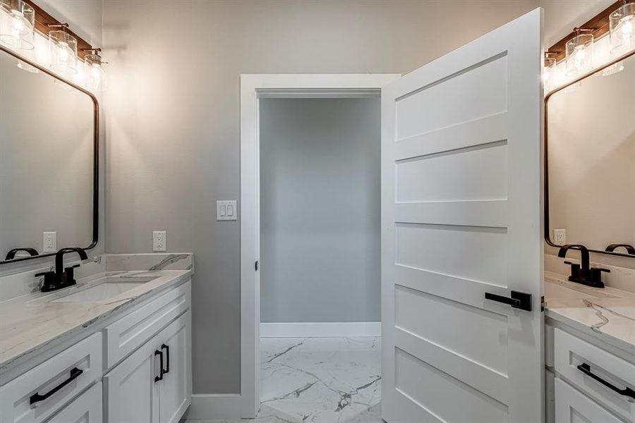 Bathroom with marble finish floor, two vanities, baseboards, and a sink