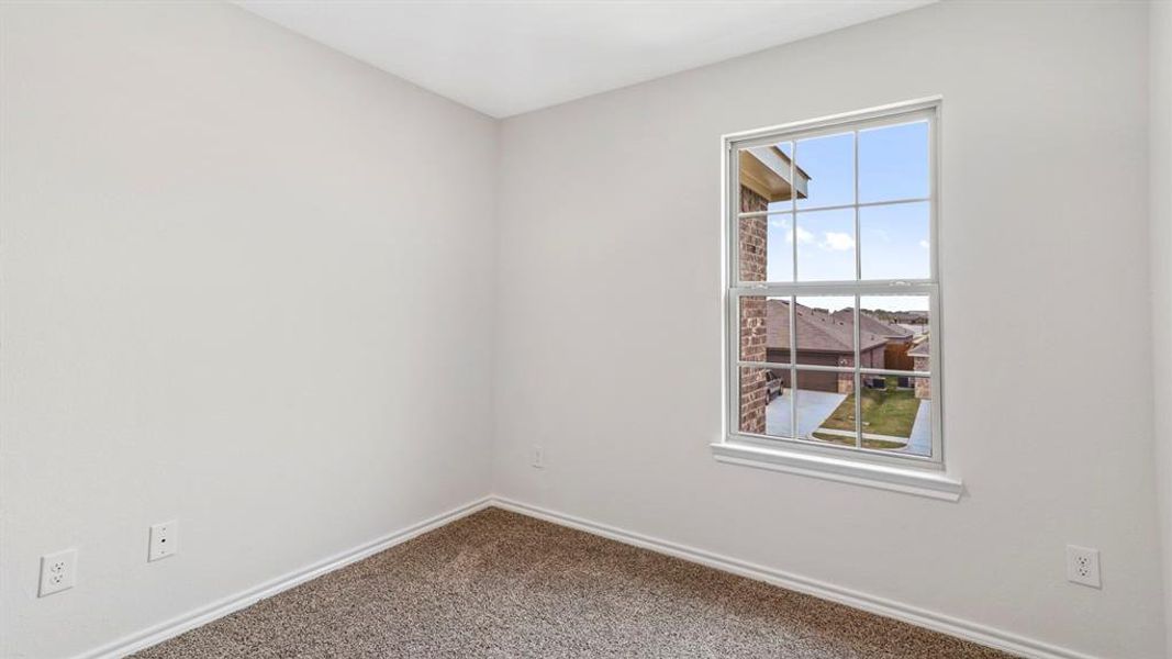 Interior room featuring neutral wall paint, white trim, textured carpeting, and a white-framed window