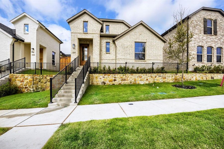 Brick facade residence featuring gabled rooflines, a stone retaining wall, and a concrete pathway leading to the entrance Brick facade residence featuring gabled rooflines, a stone retaining wall, and a concrete pathway leading to the entrance