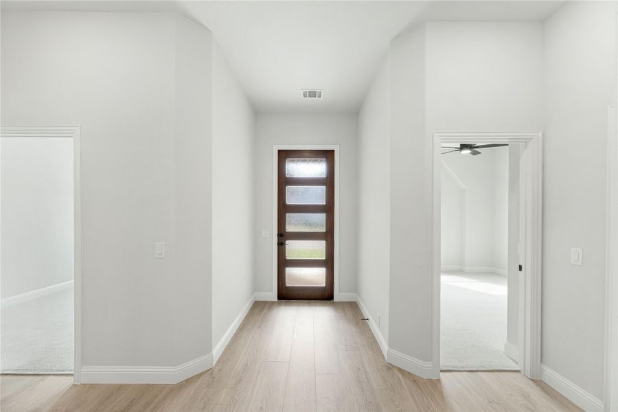 Entryway hallway with wood front door featuring glass panels and light hardwood floors