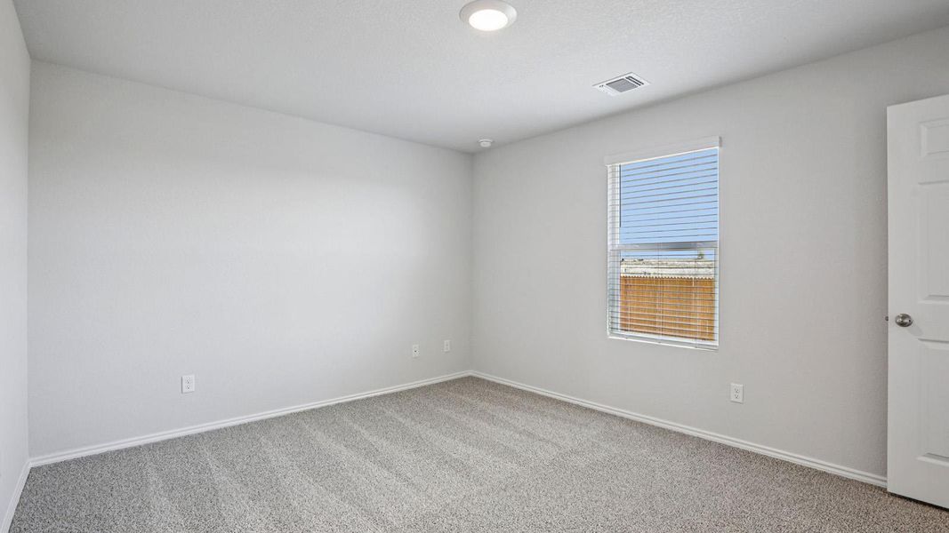 A well-lit, neutral-toned room features soft carpeting and a window offering natural illumination.