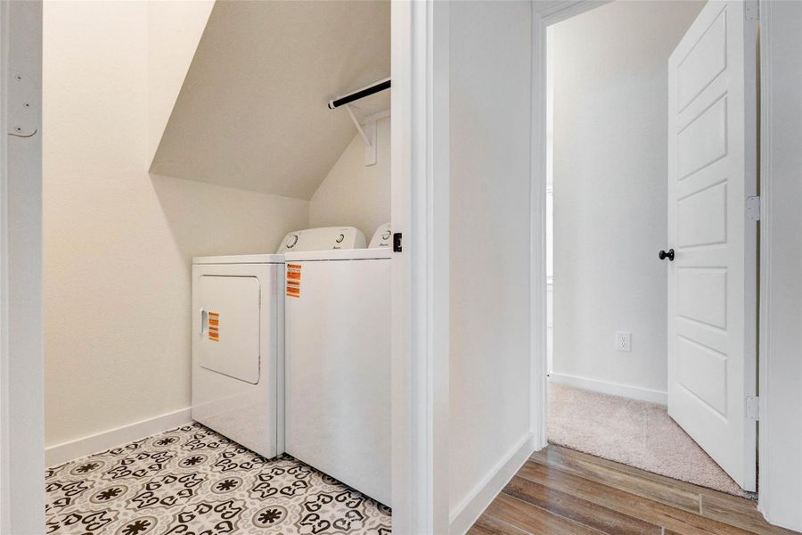 Conveniently located, this functional laundry room includes washer and dryer units set against stylish patterned tile flooring. The space is designed for efficiency with easy access and additional room for storage or organization. Bright and practical, this area adds everyday convenience while maintaining the home’s modern aesthetic.