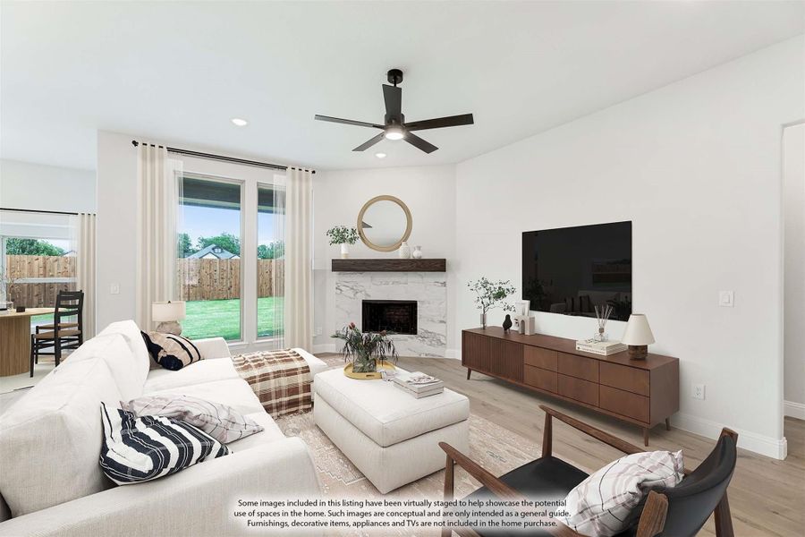 Living room with marble fireplace, hardwood floors, ceiling fan, and large windows overlooking backyard