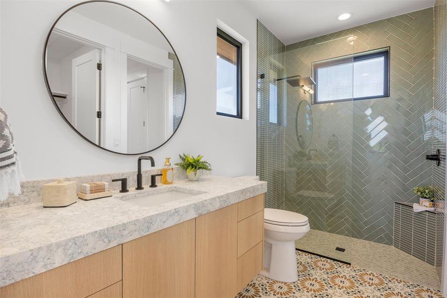 A well-appointed bathroom features a spacious vanity with an oversized mirror, alongside a sleek tiled shower.