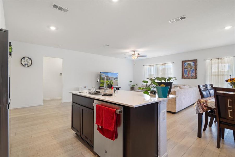 Kitchen with stainless steel appliances, open floor plan, a center island with sink, light wood-type flooring, and recessed lighting