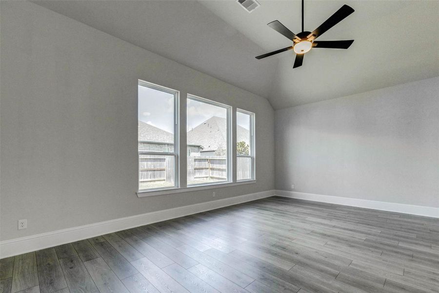 Bright, spacious primary bedroom with large windows, LVP flooring, and a modern ceiling fan.