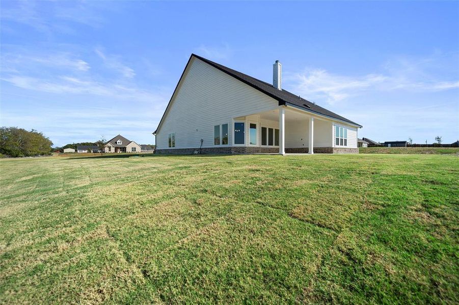 Back of house with a yard, a chimney, and a patio area