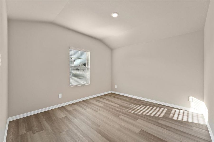 Empty room featuring lofted ceiling, light wood finished floors, and recessed lighting Empty room featuring lofted ceiling, light wood finished floors, and recessed lighting