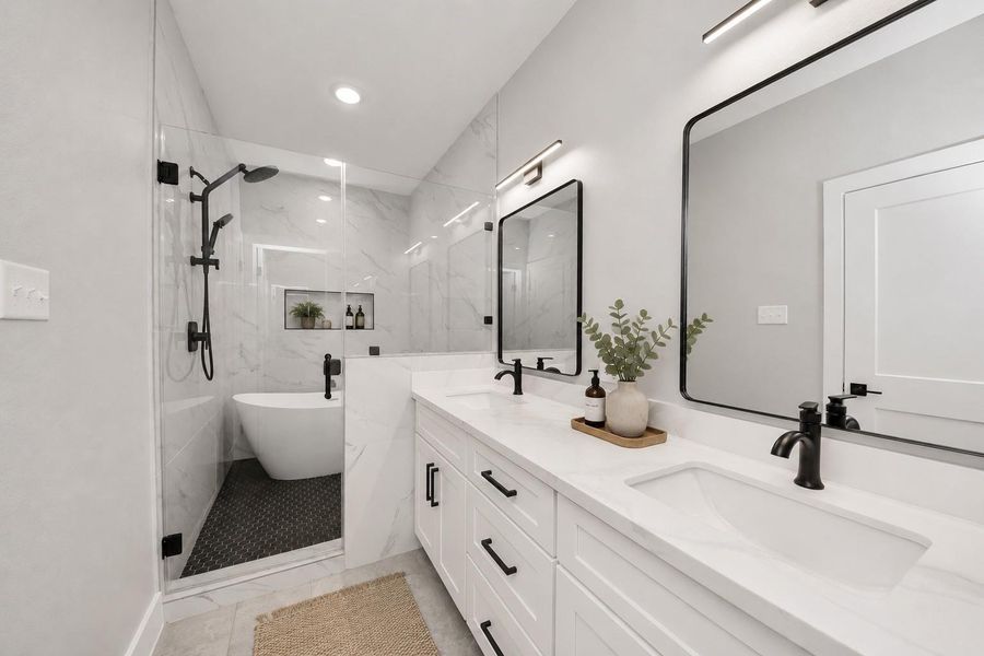Spa-inspired primary bathroom featuring dual vanities, a freestanding soaking tub, oversized walk-in shower, & sleek modern finishes throughout.