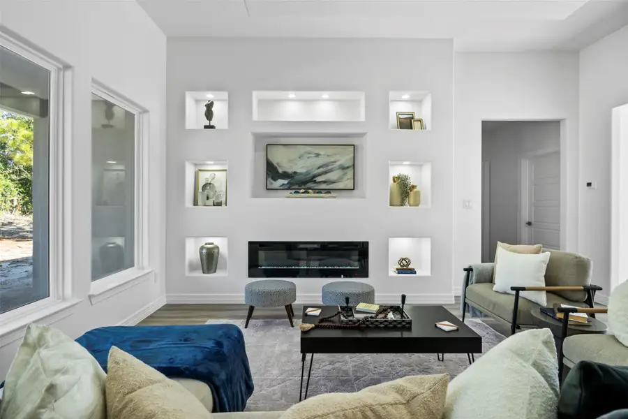 Living area with wood finished floors, a glass covered fireplace, and built in shelves
