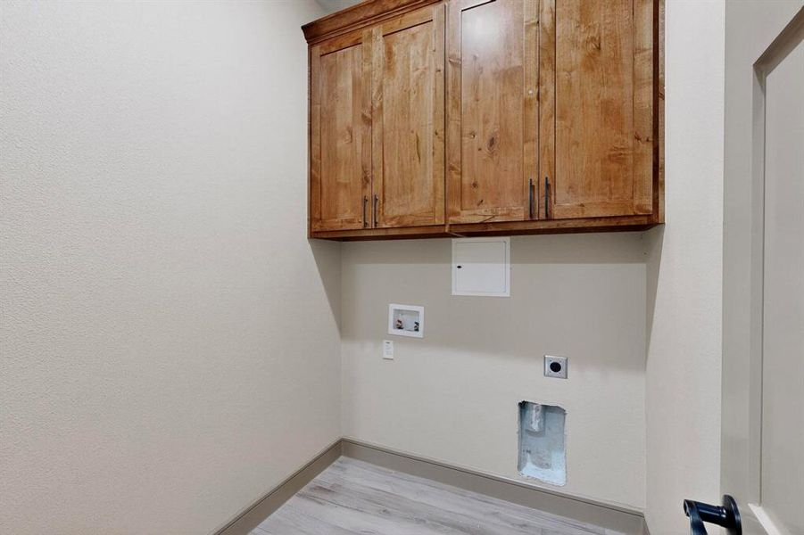Washroom with cabinet space, light wood finished floors, hookup for a washing machine, and electric dryer hookup Washroom with cabinet space, light wood finished floors, hookup for a washing machine, and electric dryer hookup
