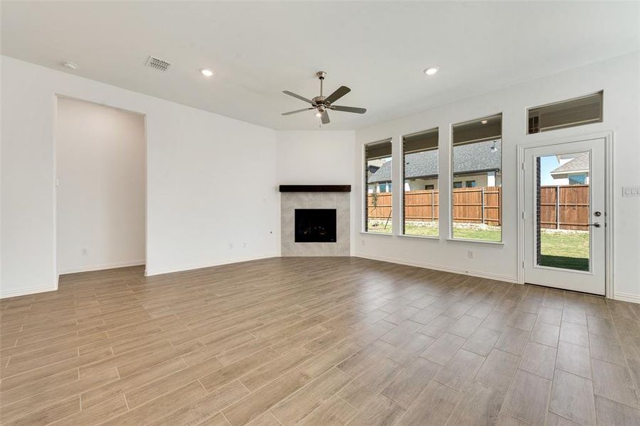 Unfurnished living room featuring ceiling fan, a fireplace, and light wood-type flooring