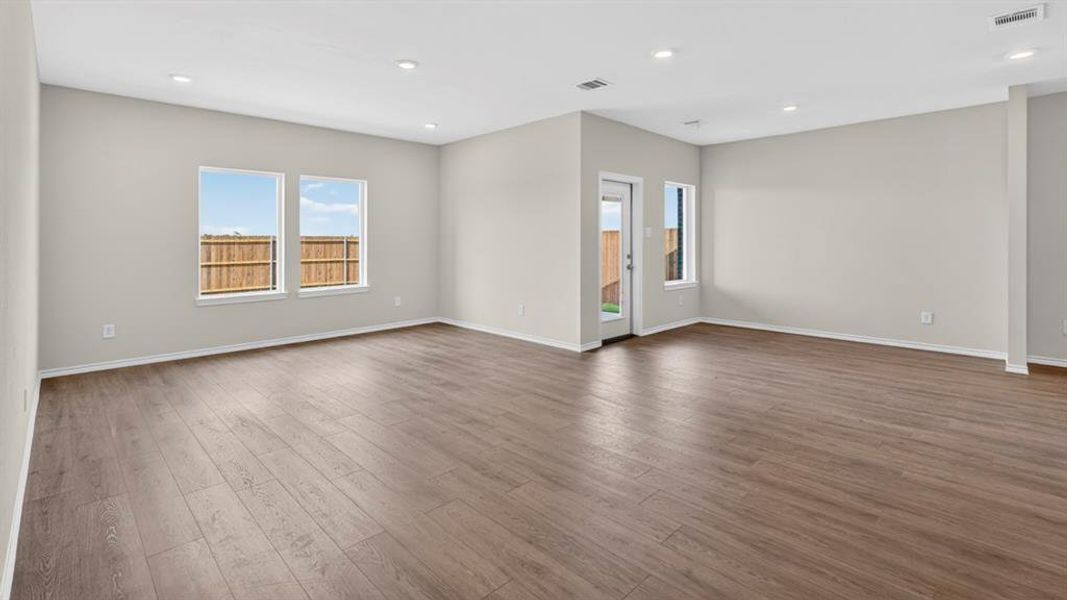 Spacious room featuring wood-finish flooring, recessed lighting, and multiple windows