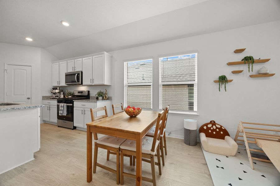 Dining area featuring light wood-style flooring, vaulted ceiling, and recessed lighting