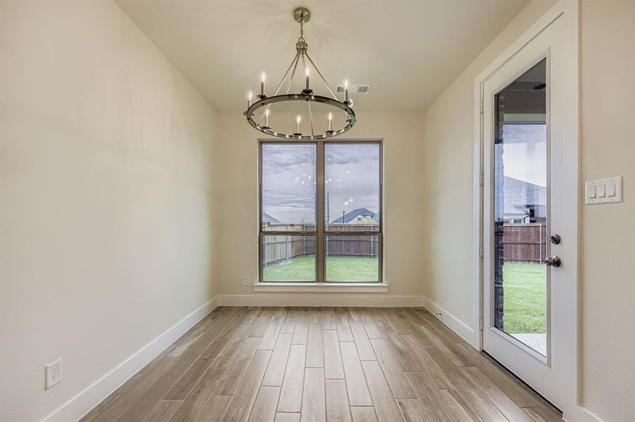 Unfurnished dining area featuring wood finish floors and a chandelier