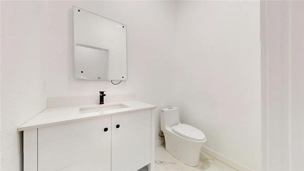 Compact bathroom featuring a white vanity with integrated sink, white countertop, and matte black faucet