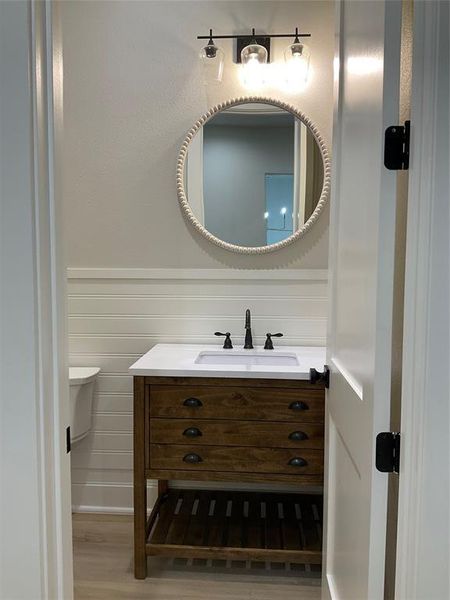 Powder room with custom sink base, shiplap wall treatment, and LVP flooring