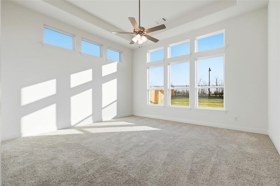 Spare room with light carpet, ceiling fan, and a high tray ceiling Spare room with light carpet, ceiling fan, and a high tray ceiling