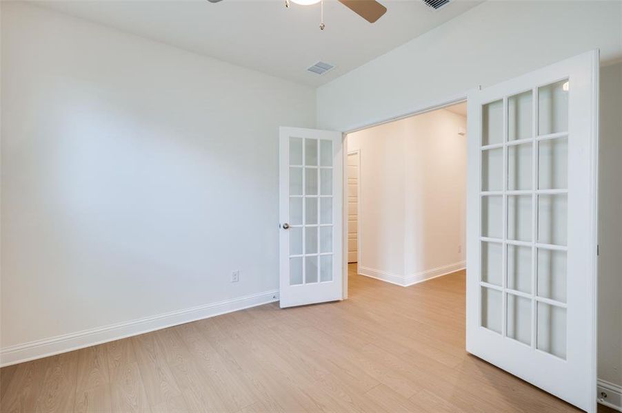 Spare room featuring ceiling fan, french doors, and light wood-type flooring