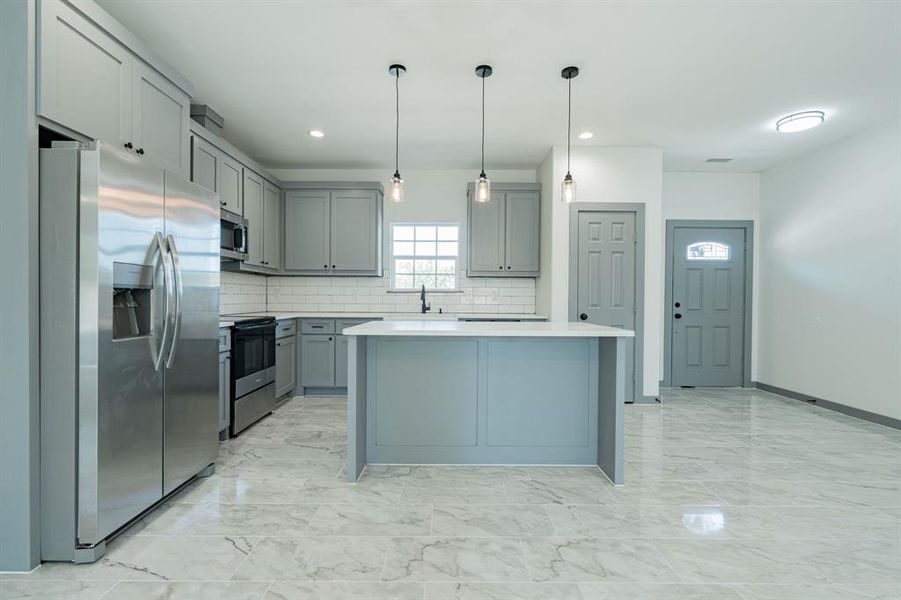 Kitchen with stainless steel appliances, decorative backsplash, pendant lighting, light tile patterned floors, and gray cabinets