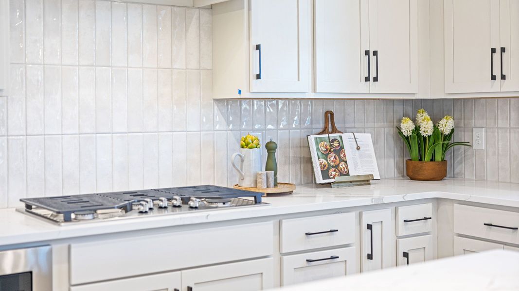Kitchen with quartz countertops, tile backsplash, and light cabinetry