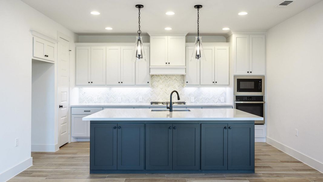 Kitchen featuring white cabinetry, recessed lighting, stainless steel oven, an island with sink, and light wood-style flooring Kitchen featuring white cabinetry, recessed lighting, stainless steel oven, an island with sink, and light wood-style flooring
