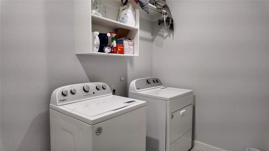 The laundry area includes a white top-loading washing machine, a white front-loading dryer, a white wall-mounted shelf, and a wall-mounted clothes rack