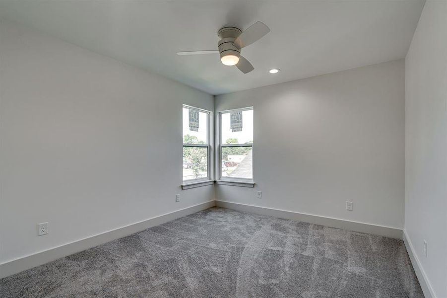 Carpeted empty room featuring ceiling fan