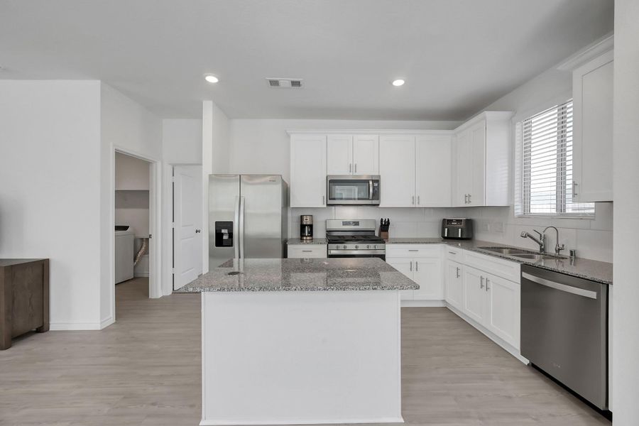 Kitchen features granite counter, island with phone charger on top, stainless stell appliances and gas 5 burner stove.