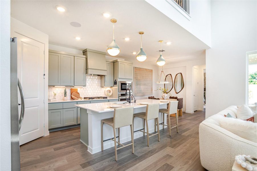 A modern, open-concept kitchen and living area. The kitchen features sleek cabinetry, a large island with seating, and stylish pendant lighting. A modern, open-concept kitchen and living area. The kitchen features sleek cabinetry, a large island with seating, and stylish pendant lighting.