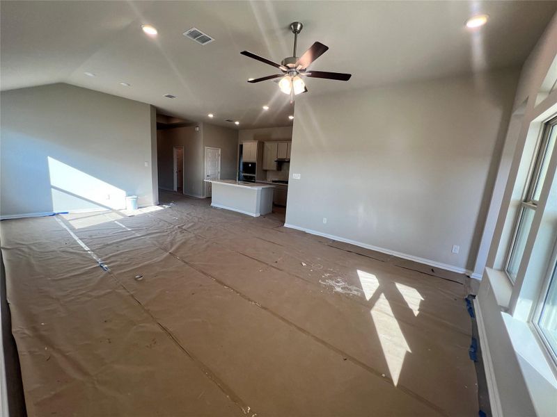 Unfurnished living room featuring vaulted ceiling, ceiling fan, and recessed lighting