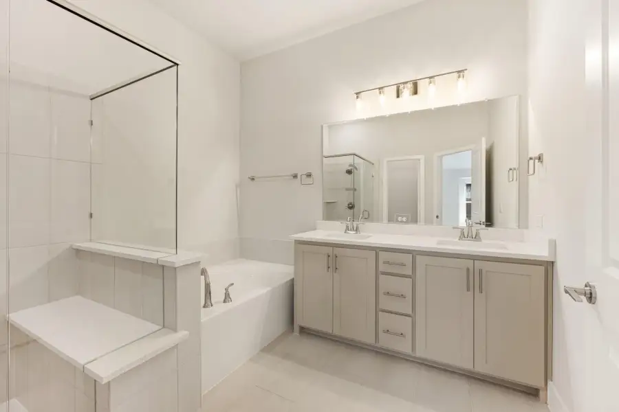 Master bathroom with double sink vanity, soaking tub, and glass shower enclosure with white tile