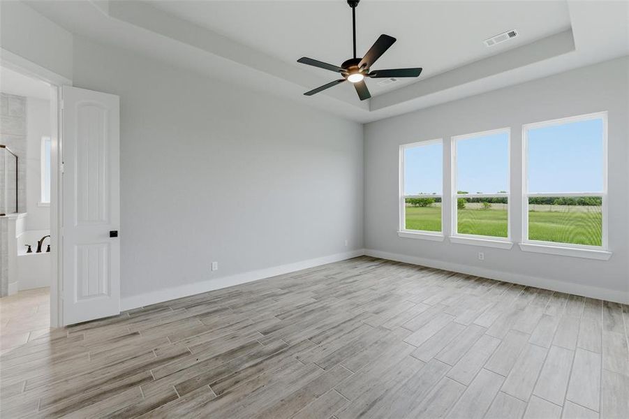 Spacious interior featuring wood-look tile flooring, a tray ceiling, and a ceiling fan