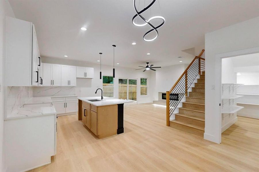 Kitchen featuring open floor plan, decorative light fixtures, light wood finished floors, a kitchen island with sink, and recessed lighting Kitchen featuring open floor plan, decorative light fixtures, light wood finished floors, a kitchen island with sink, and recessed lighting