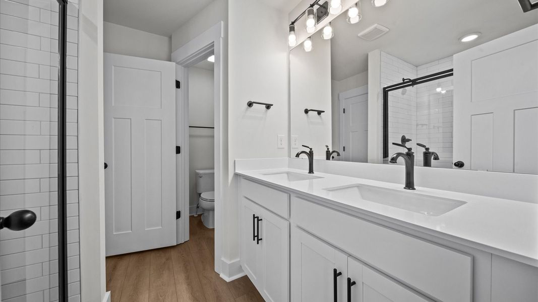Stunning primary bathroom with white quartz double sink vanity in two story townhome at Ransdell Pointe by DRB Homes Stunning primary bathroom with white quartz double sink vanity in two story townhome at Ransdell Pointe by DRB Homes