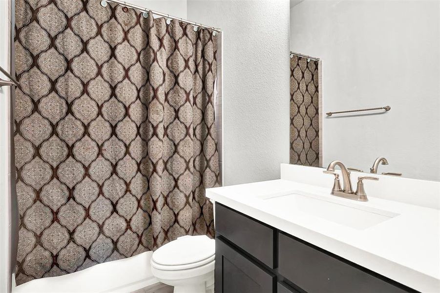 Full bathroom featuring vanity, a shower with curtain, and a textured wall