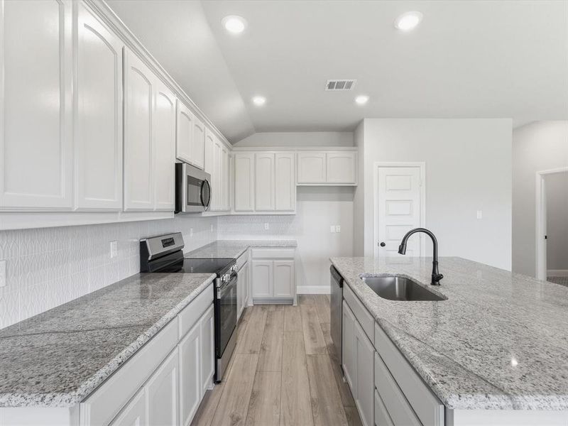 Modern kitchen featuring an extended island with a built-in sink and dark-finish faucet Modern kitchen featuring an extended island with a built-in sink and dark-finish faucet