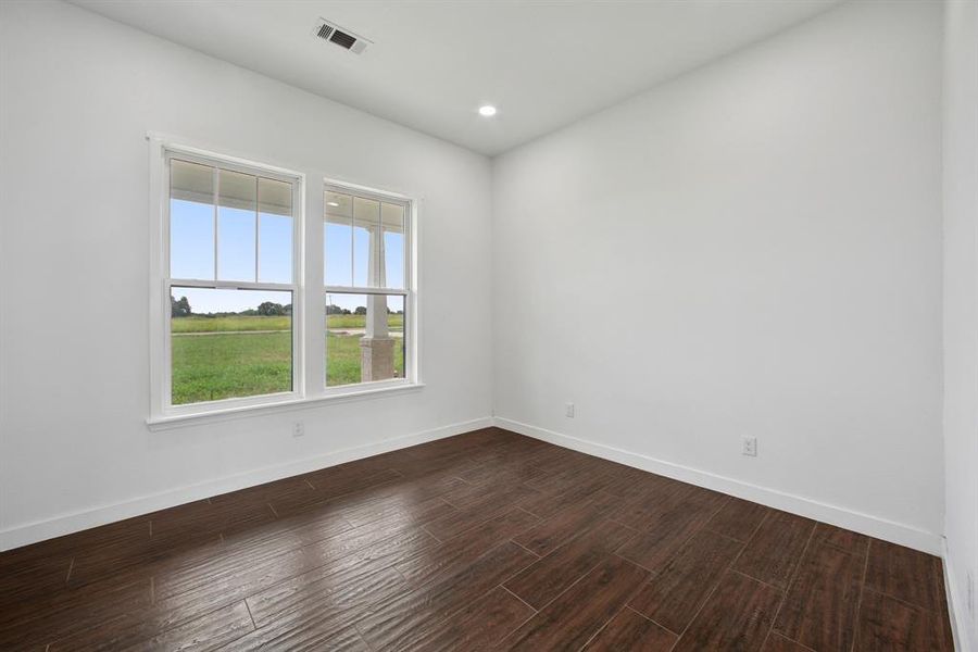 Empty room with dark wood-style flooring and recessed lighting