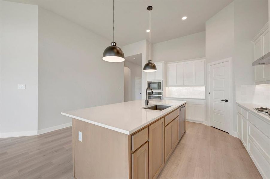 Kitchen island with a stainless steel undermount sink, matte black faucet, and two pendant lights
