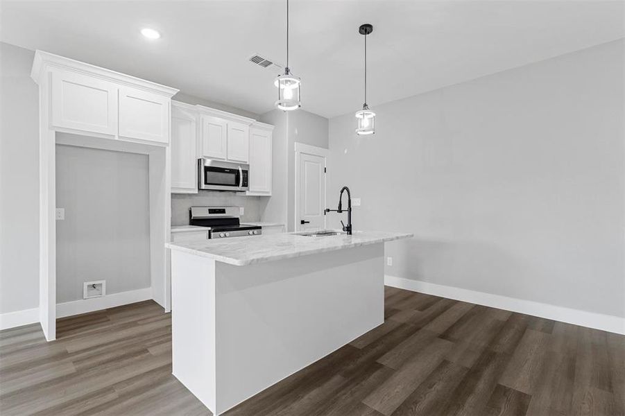 Kitchen featuring light stone countertops, dark hardwood / wood-style flooring, appliances with stainless steel finishes, decorative light fixtures, and backsplash